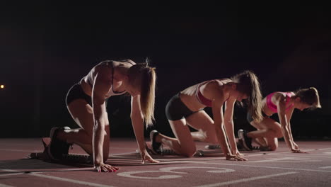 Cámara-Lenta-3-Corredoras-Corriendo-Hacia-La-Cámara-En-Un-Estadio-Deportivo.-Competición-De-Atletismo-De-Atletismo-Corriendo-En-La-Oscuridad.-Correr-Juntos